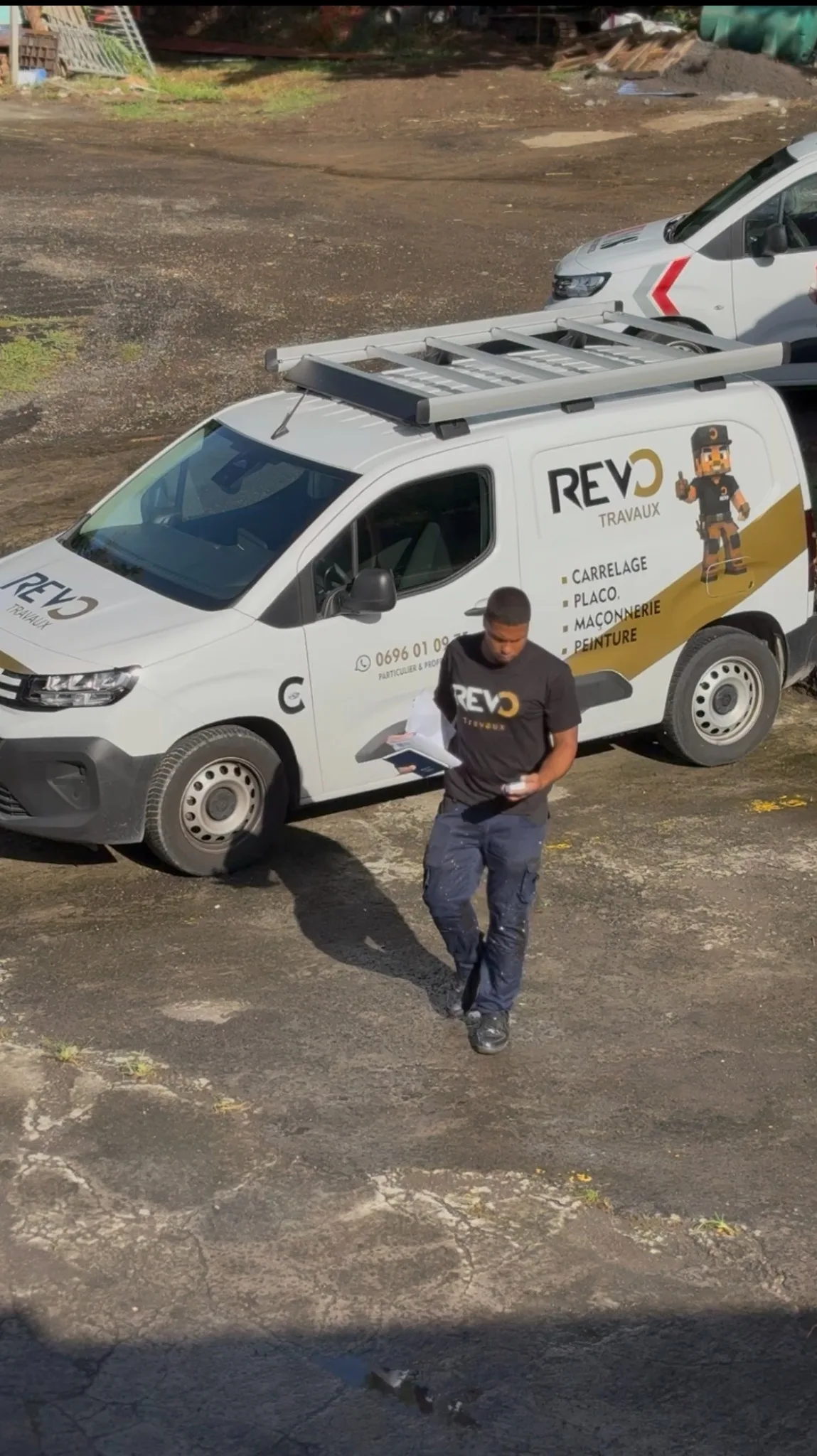 Un membre de l'équipe REVO TRAVAUX en tenue de travail devant le véhicule de l'entreprise